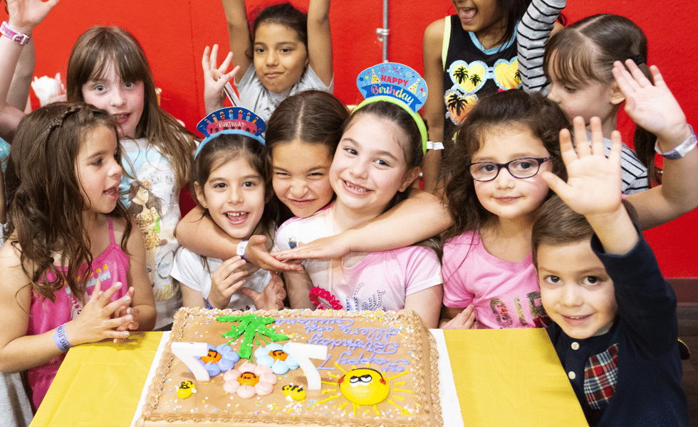 Children celebrating a birthday with cake and party hats