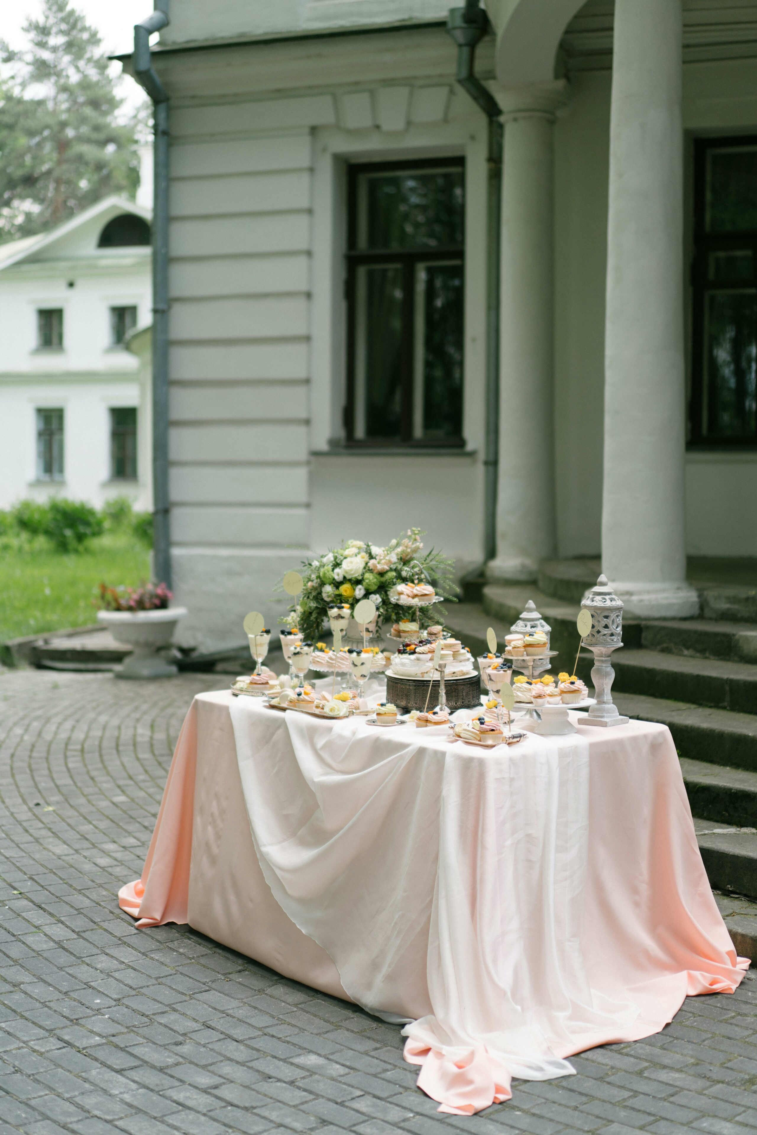 Outdoor dessert table with cakes and pastries by a house