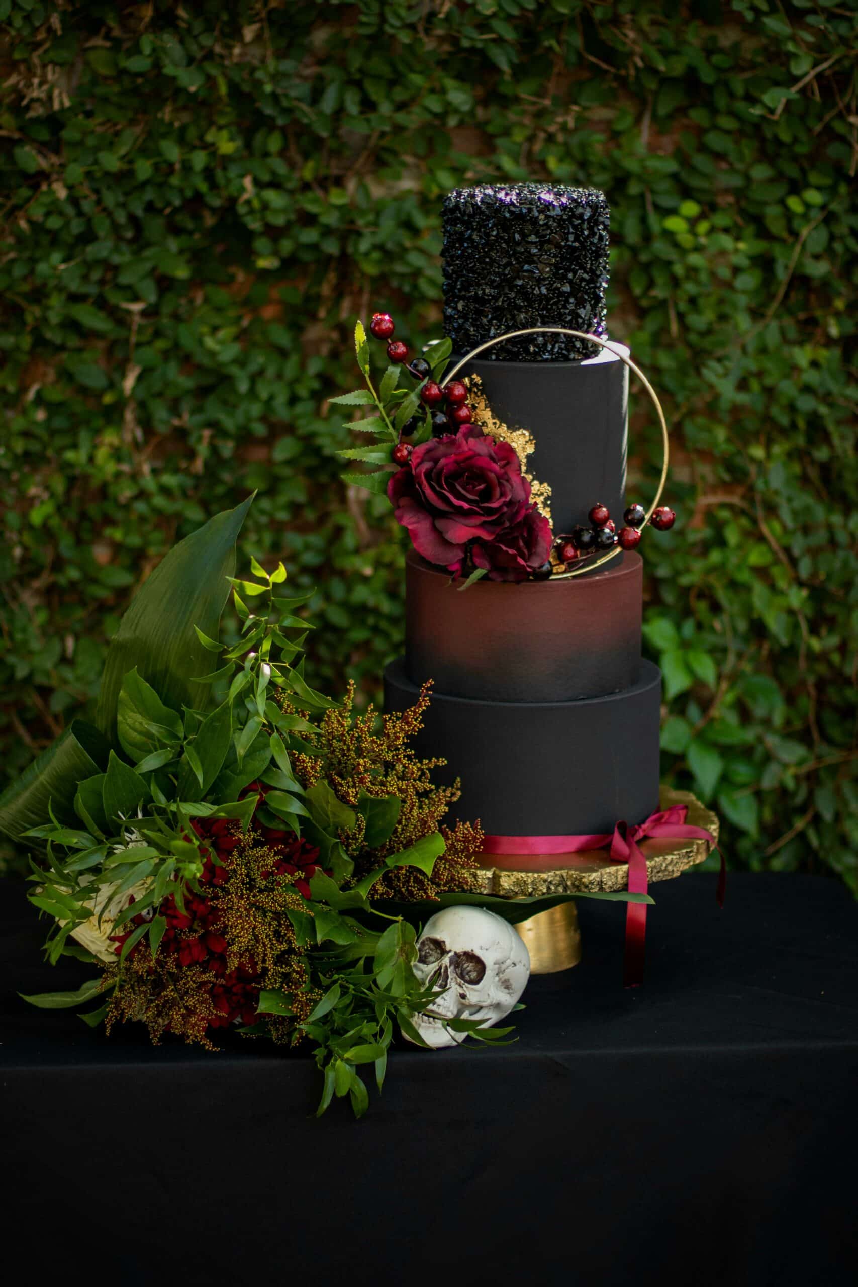 Dark tiered cake with red flowers and gothic style decorations