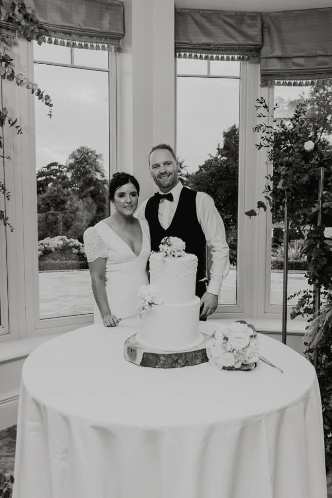 Bride and groom posing with wedding cake indoors