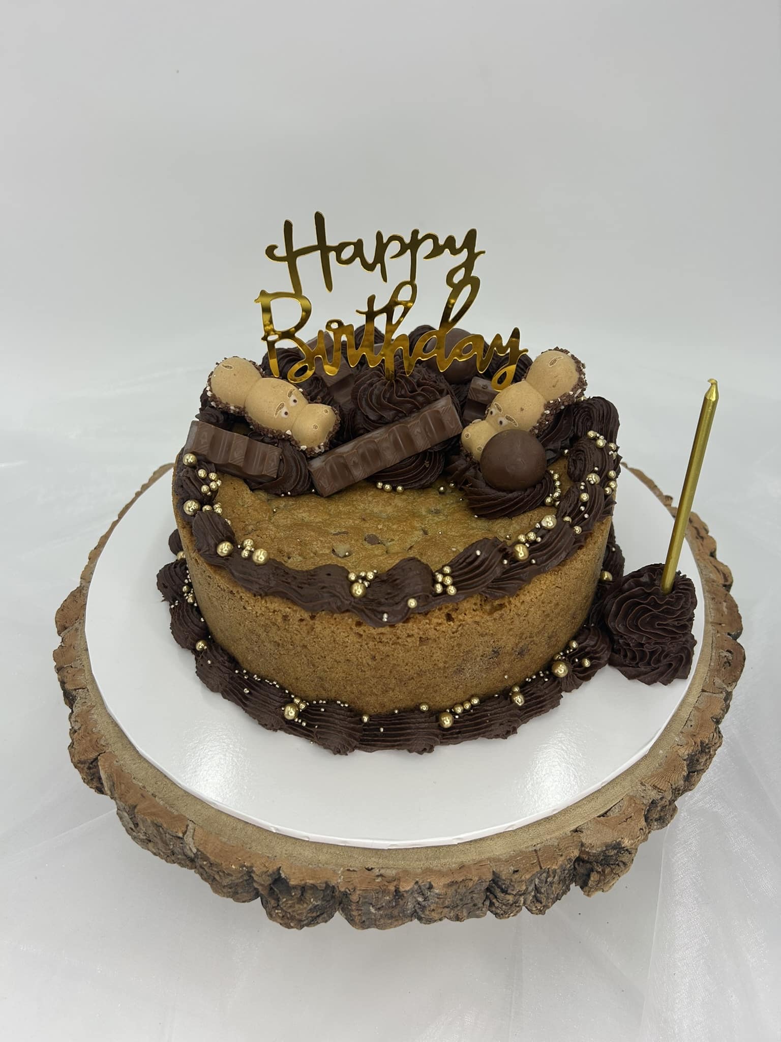Chocolate birthday cake with sweets and gold “Happy Birthday” topper