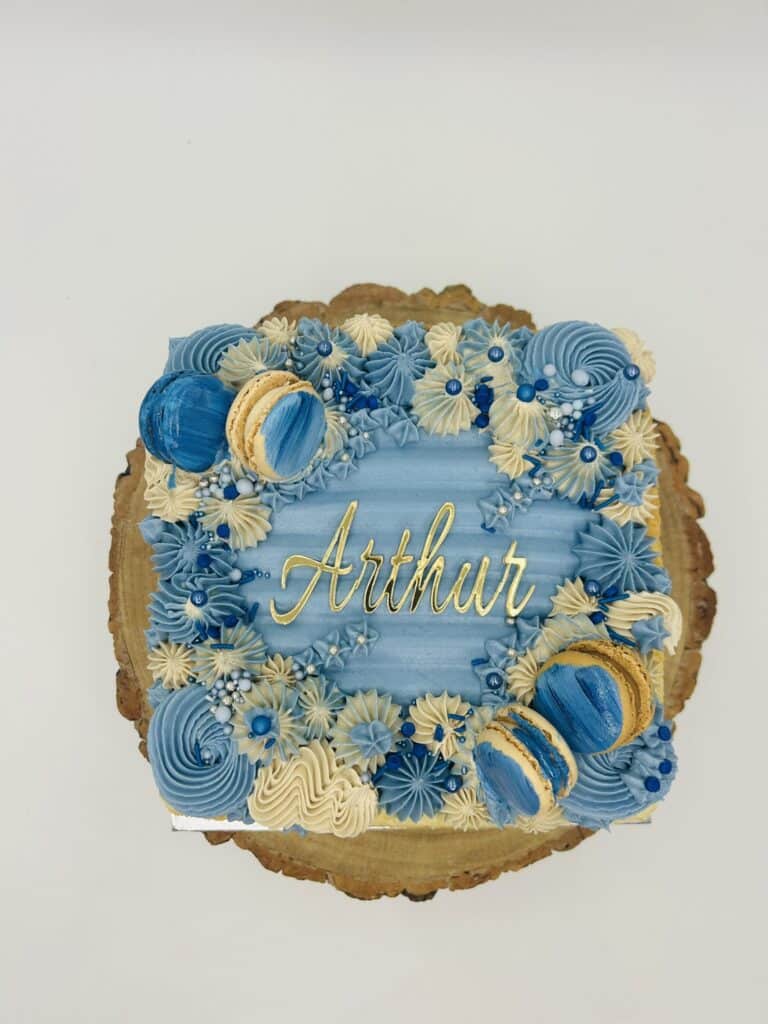 Blue birthday cake with macarons and “Arthur” name topper