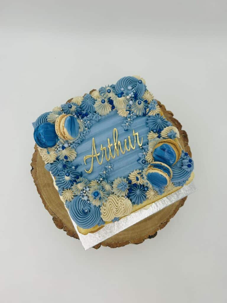 Blue birthday cake with macarons and “Arthur” name topper