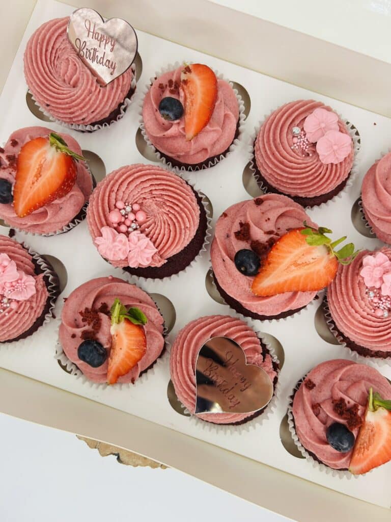 Pink cupcakes with strawberries and blueberries in a box