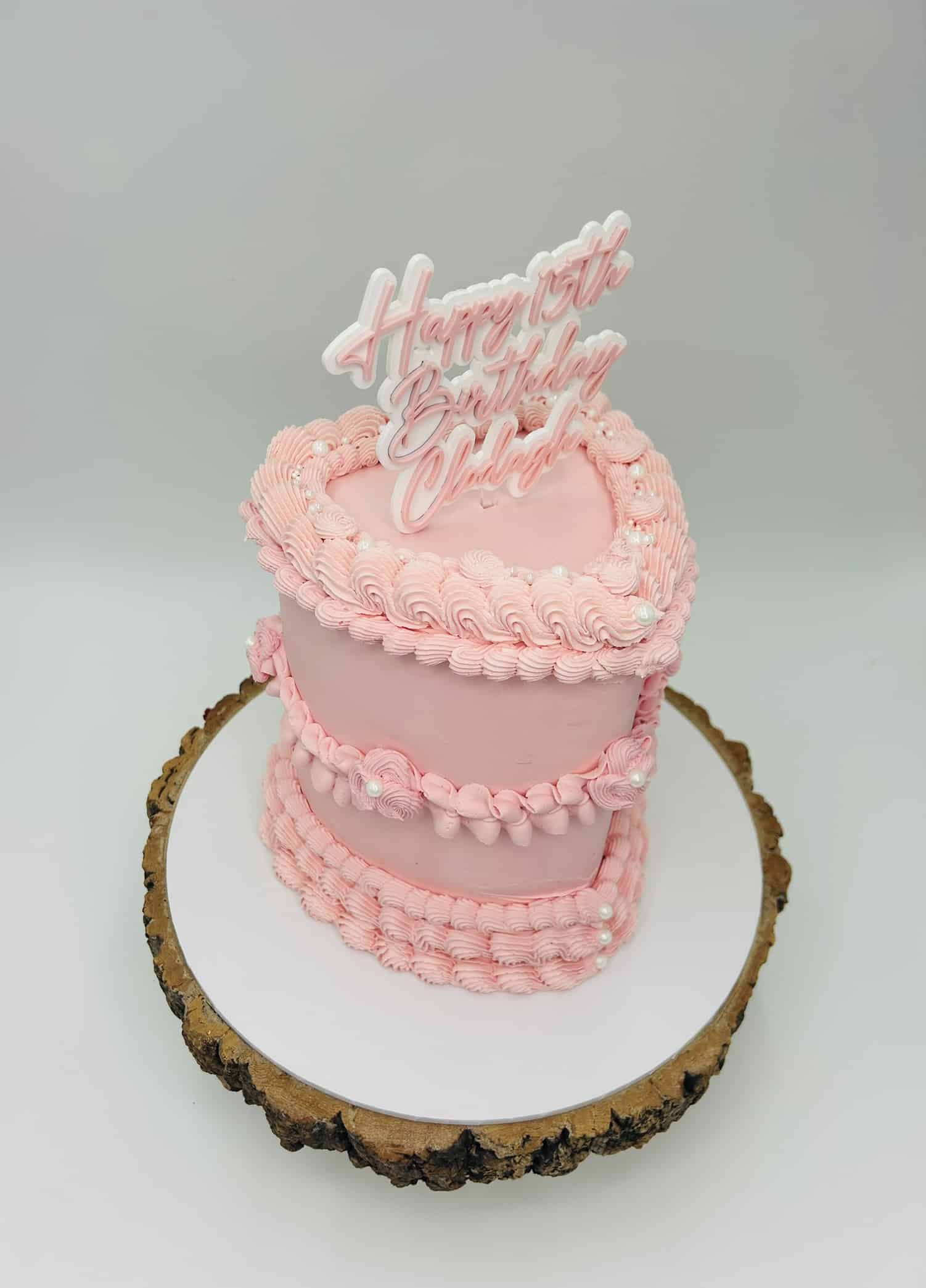 Pink birthday cake with piped icing and topper