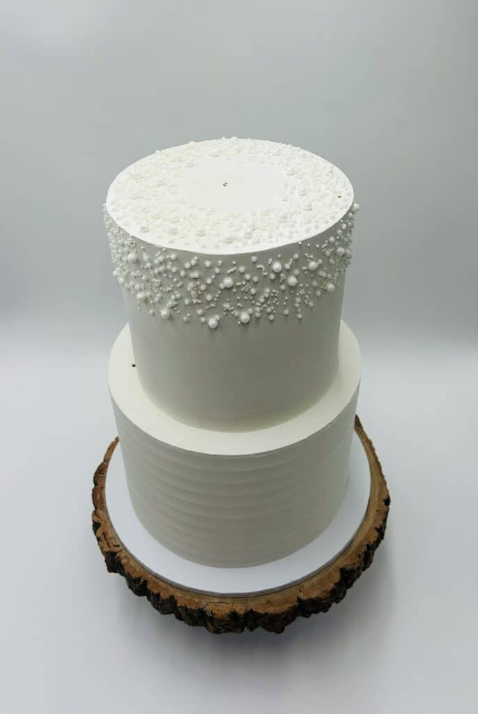 Two-tier white cake with textured icing and pearl decorations