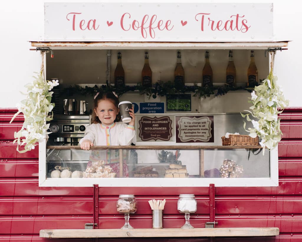 Child serving coffee at tea and treats trailer counter