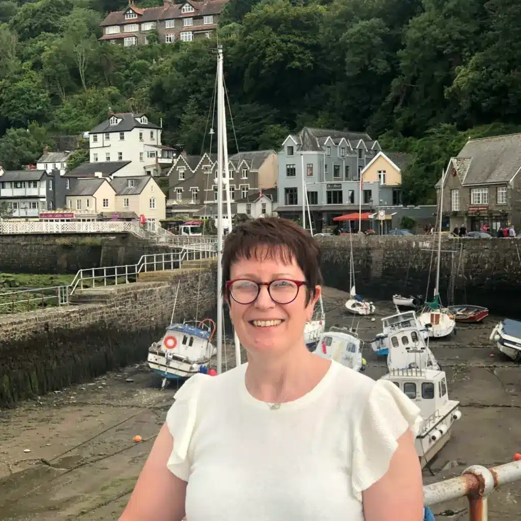 Woman smiling at harbour with boats and hillside houses