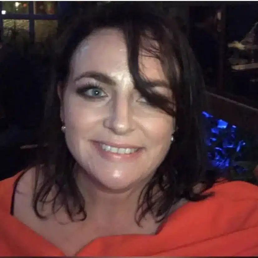 Woman smiling in a red top indoors at night