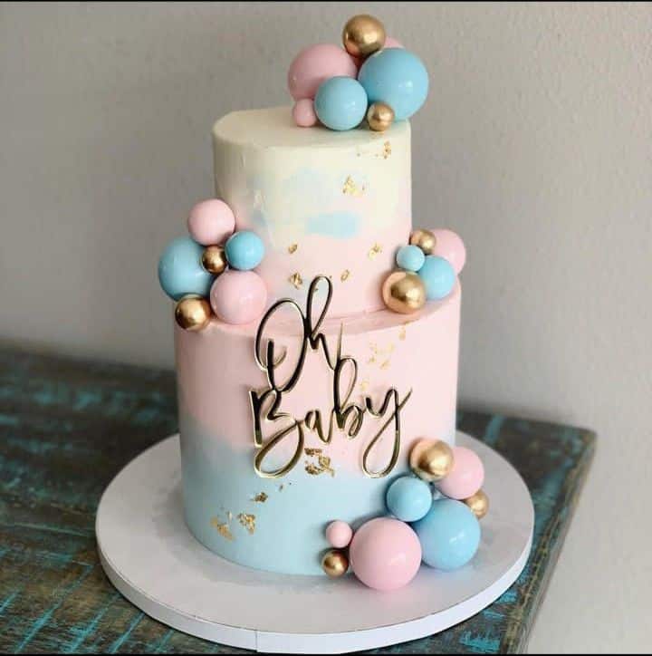 Pastel gender reveal cake with “Oh Baby” topper and balloon decorations