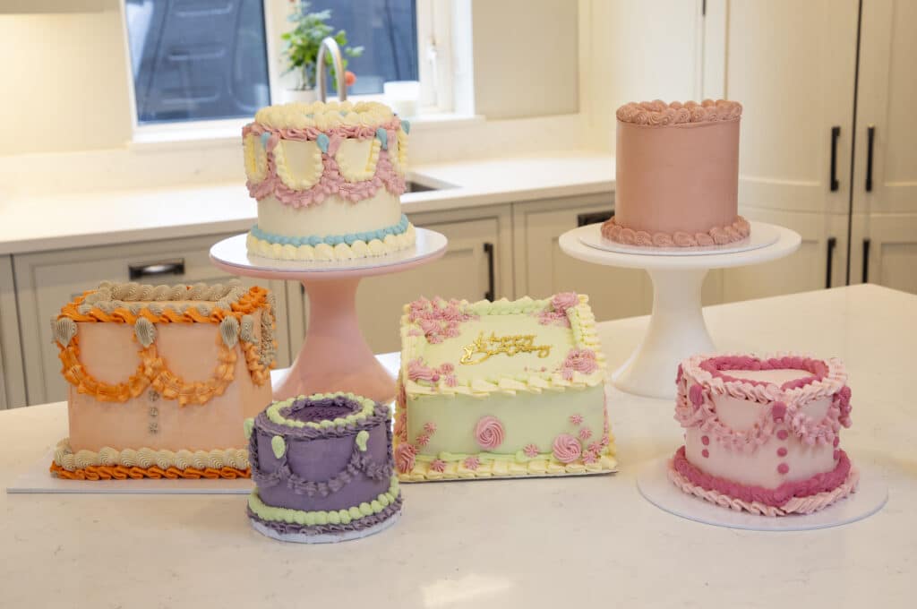 Assorted classic cakes with pastel icing displayed on stands