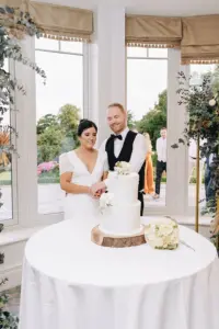 Bride and groom cutting a white wedding cake indoors